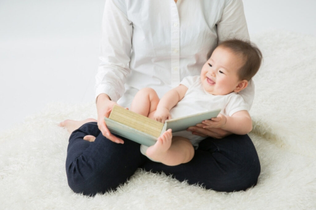 赤ちゃんに本を読み聞かせるママ